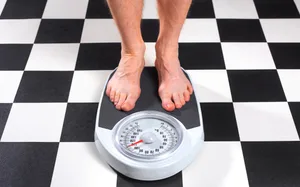 Overweight Man Standing on Bathroom Scales Senior obese man measuring his weight on bathroom scales