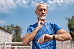Senior Athlete Taking Pulse at the Stadium Confident senior athlete after running at the sports stadium on a running track taking a break taking pulse