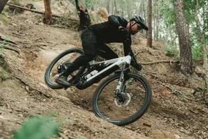 Megamo Ryal eMTB Mountain biker riding through a dry, dusty singletrack turn on a white Megamo Ryal eMTB.