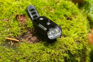 Lezyne Super Drive 1800+ Smart front light Lezyne Super Drive 1800+ Smart mountain bike front light resting on moss with its rubber handlebar strap visible.