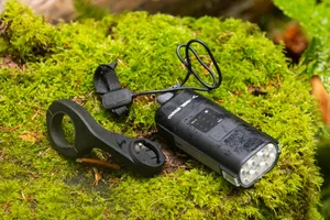 Moon Rigel Enduro 2600 front light with remote and mount Moon Rigel Enduro 2600 mountain bike front light with wired remote and handlebar mount resting on moss.