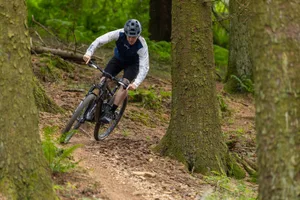 Lauf Elja – cornering Male rider in blue and white top riding the Lauf Elja XC Ultimate Flight Attendant full suspension mountain bike