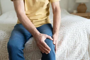 Unrecongnizable senior man holding his knee while suffering pain Older person struggling with knee pain