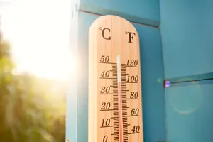 Thermometer at blue wooden wall in garden A thermometer on the wall with the Sun in the background