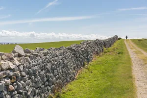 Hiking on Lundy Island A distant hiker on the dirt road following a stone wall on top of Lundy Island, Devon, UK.