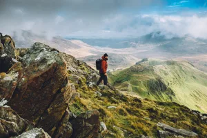 The journey home A hiker wearing a backpack walking down a steep hill