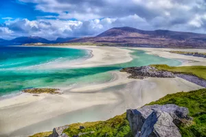 Fresh Perspectives on the Classic Hebridean view of Luskentyre from Seilebost on the Isle of Harris, NW Scotland in early Summer 2021 Beaches at Luskentyre on Eilean Siar in the Western Isles or Outer Hebrides (The Isle of Harris, specifically), off North West Scotland in the UK. Taken in midmorning, early May 2021 during an unusually prolonged winter. Both images show dramatic storm clouds building over the North Harris hills but these are casing shadows and unusual light where the hills meet the sea. The sand and sea at this world famous viewpoint are constantly shifting such that a new sandbank has developed and allowed the Jade Green seas to create new routes over the dazzling white sand. The two pictures are broadly similar but the second one is arguably more dramatic, given the shooting in HDR. In the first picture illustrates the deep cobalt blue sea, fading towards the hills as deep emerald but then fades further still to paler Jade in the shallowest areas. The second picture was taken in HDR and really emphasises the already vivid colours of the water, the rocks and the sand.