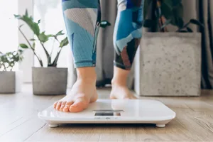 Brown fat weight loss A close up of bare feet standing on a scale at home