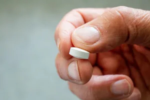 man holding statin Person holding a statin pill.
