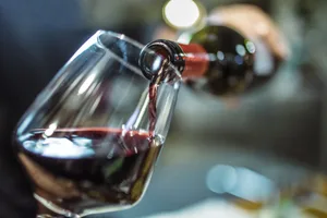 pour red wine Pouring bottle of red wine into a glass.
