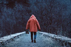 doomsday Man with orange coat walks into forest.