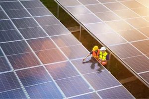 Solar Panels Two people in hardhats and hi-vis vests look at solar panels