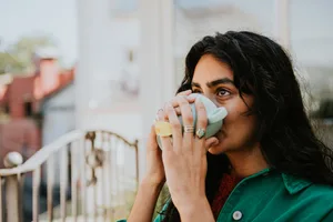 hot-drink-health A woman cups her hands around a mug and drinks the brew