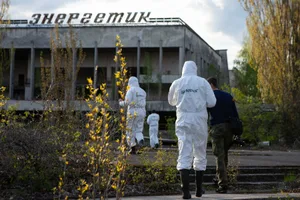 chernobyl-discoveries People wearing hazmat suits with inscriptions ‘Greenpeace’ take pictures of the abandoned Palace of Culture Enerhetyk in the city center on April 25, 2016 in Prypiat, Ukraine (Chernobyl)