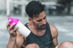 Mixing a Protein Shake after Exercising A man is sitting down to mix a protein shake after en exercise inside an abandoned warehouse.