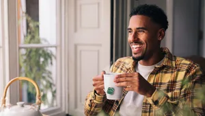 Medium-933825-116760-NPD_LaunchLifestyle_Image_Updates_Retouch_LG_DM_Retouch_EEE A young black man smiles while holding a cup of tea.