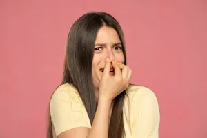 woman farting smell Portrait of frustrated woman pinching nose with disgust on his face due to bad smell isolated over pink background.