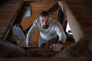 man climbing into attic A man climbs up a ladder into an attic