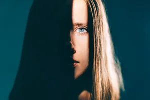 psychopath eye Close-up of a woman’s face partially obscured by shadow, with one eye visible and long hair framing her face.