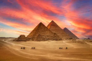 giza-egyptian-pyramids Great Pyramids in Giza, Egypt, with a camel caravan in front