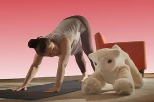Familiar-stretch Photo of a person stretching on a yoga mat. A furry robot Familiar is beside them also stretching