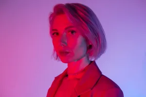 dark-triad-personalities closeup portrait of a calm woman looking at the camera in neon light