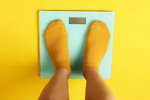 fat-loss-rules Photo of someone in a pair of yellow socks standing on a blue set of scales.