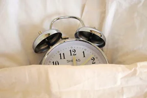 11-more-minutes-sleep Photo of an alarm clock tucked up in bed under a duvet