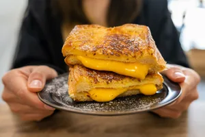 Cheese (1) Two hands hold a plate with a cheese toastie on top