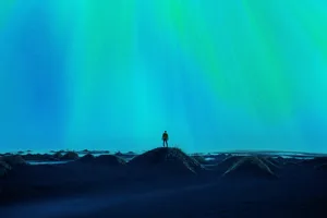 Northern Lights Blue and green lights shine from the sky by a silhouette of a person