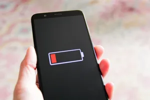 Phone with low battery Hand holding a mobile phone which shows low battery sign on screen