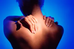 The vagus nerve Woman touching the back of her shoulders to relieve stress