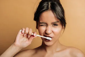 Dental advice A woman brushing her teeth against a brown background