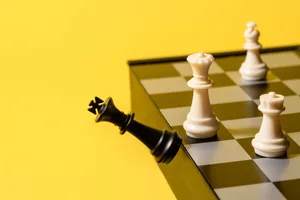 How to win an argument A black king chess piece is falling off a chess board against a yellow background