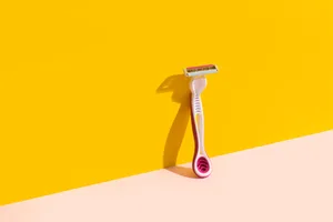 A pink razor against a yellow and light pink background A pink razor against a yellow and light pink background