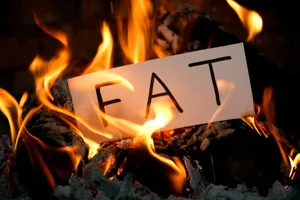How to burn fat without losing muscle A piece of paper with the word "FAT" written on it is being engulfed by flames