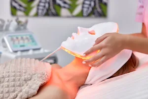 LED face masks A woman receiving a red light therapy treatment in a beauty salon