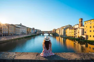 A woman looking out at a river in a sunny city A woman looking out at a river in a sunny city
