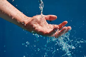 cold water therapy A hand in running water against a blue background