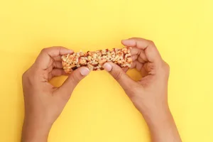 Hands holding a cereal bar on a yellow background Hands holding a cereal bar on a yellow background