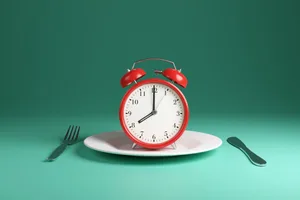 6 morning routines that will trigger weight loss (1) A red alarm clock sits on a dinner plate next to a knife and fork against a green background