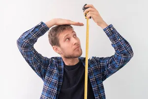 A man measuring himself with a tape measure A man measuring himself with a tape measure