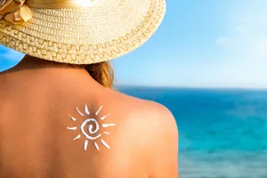 A sun drawn in suncream on a woman's back A sun drawn in suncream on a woman's back