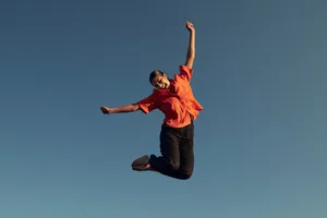 A woman jumping in the air, against a blue background A woman jumping in the air, against a blue background