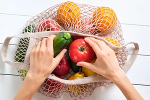 Woman grabs vegetables out of sustainable bags Woman grabs vegetables out of sustainable bags