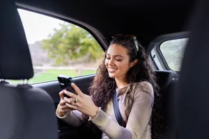 Motion sickness trick Woman looking at her phone and smiling in a car