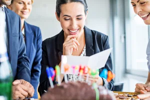 business-greeting-header Businesswoman reading birthday card during birthday celebration in office.