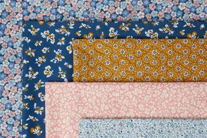 Your comprehensive guide to high-quality fabrics A collection of five floral fabric swatches, each with distinct patterns and colors, is neatly arranged. The fabrics feature blue, pink, mustard, and white hues, showcasing intricate floral designs on each piece.