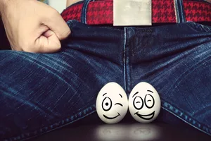 Testicle facts Two eggs featuring smiley faces are positioned in front of a man's crotch
