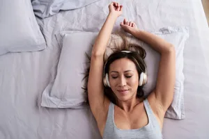 Audio erotica A woman is lying on a bed wearing headphones